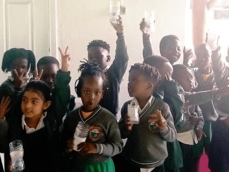 Children in classroom holding up water bottles.