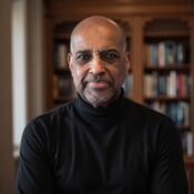 Andrew Neves in his library wearing a dark jacket over a turtleneck sweater